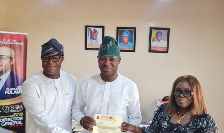 DG-OYSIPPA-Mr.-Tilewa-Folami-handing-over-the-Mandate-Letter-of-Grant-to-Engr.-Yinka-Owodunni.-With-them-is-the-Permanent-Secretary-Ministry-of-Lands-Mrs.-Modupe-Adebiyi